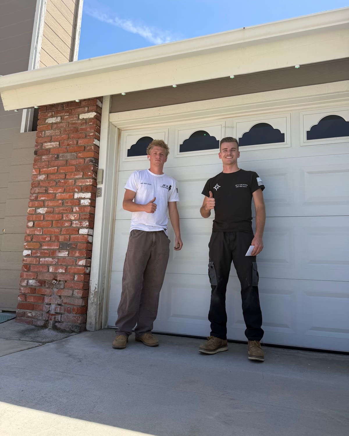 Two members of the JFX Lighting team standing in front of a garage
