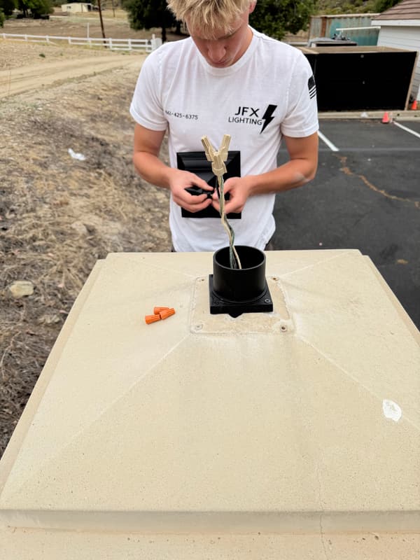 JFX Lighting team member wiring a post-top light fixture onto a column cap