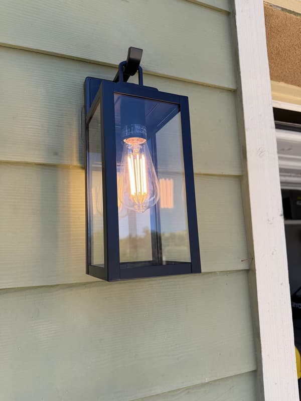 Black lantern-style wall sconce with an exposed filament bulb