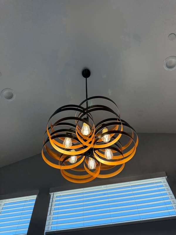 Black and gold ribbon chandelier with exposed bulbs under a vaulted ceiling